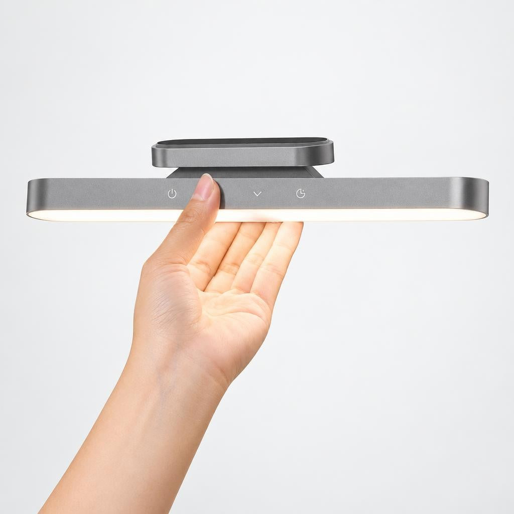 Under cabinet light with touch controls held in a hand against a plain background