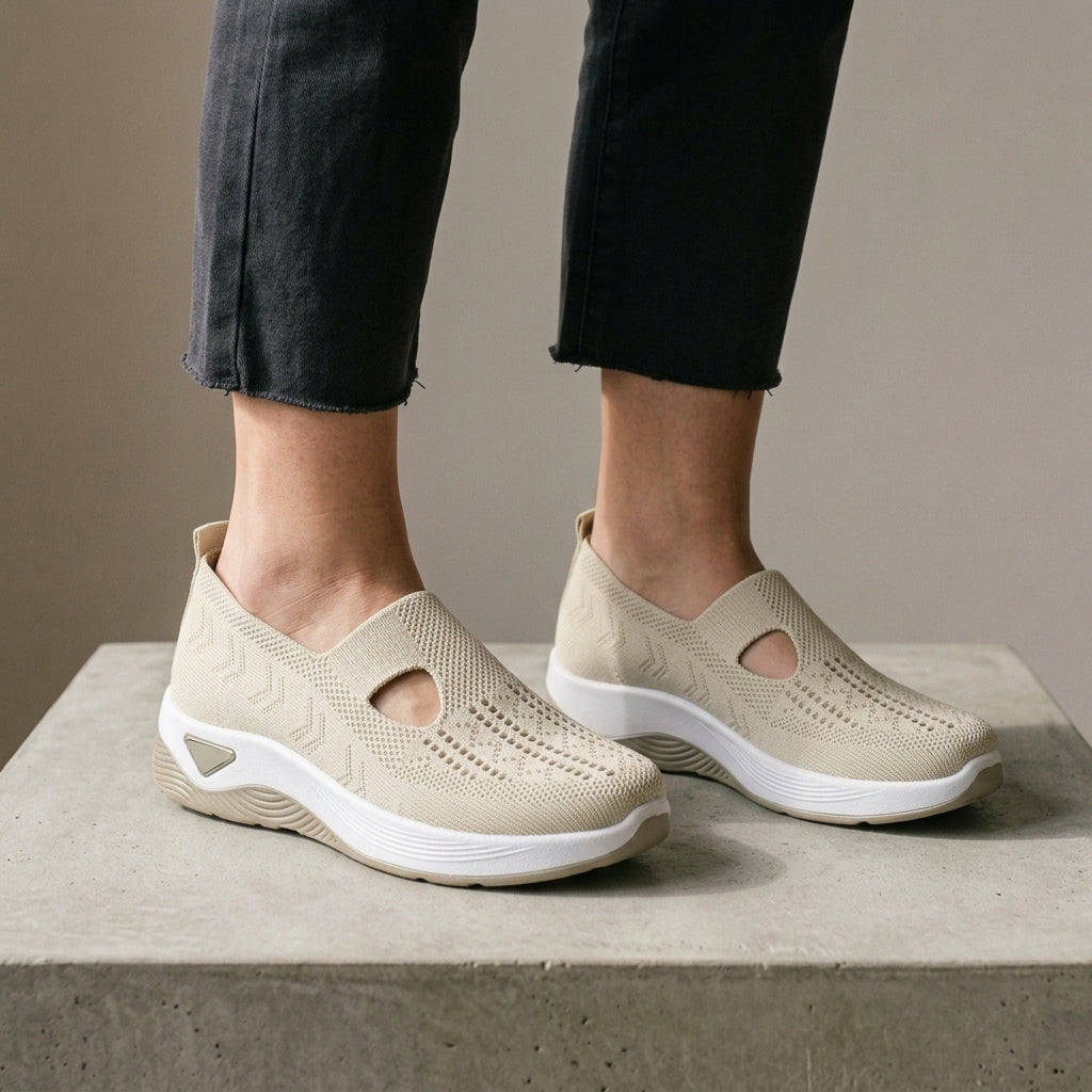 Cream mesh knit sneakers worn with grey jeans.