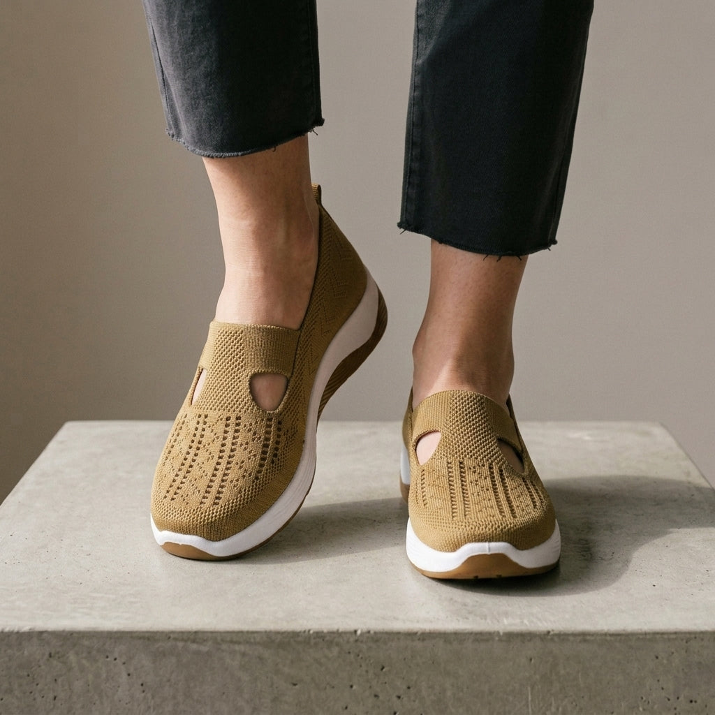 Khaki mesh knit sneakers worn with grey jeans, one foot raised.