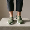 Army Green knit sneakers women can wear daily, front view worn with grey cropped jeans.