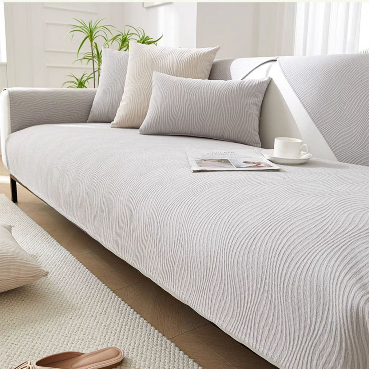 Pale grey wave-textured sofa cover with matching cushions on a modern sofa