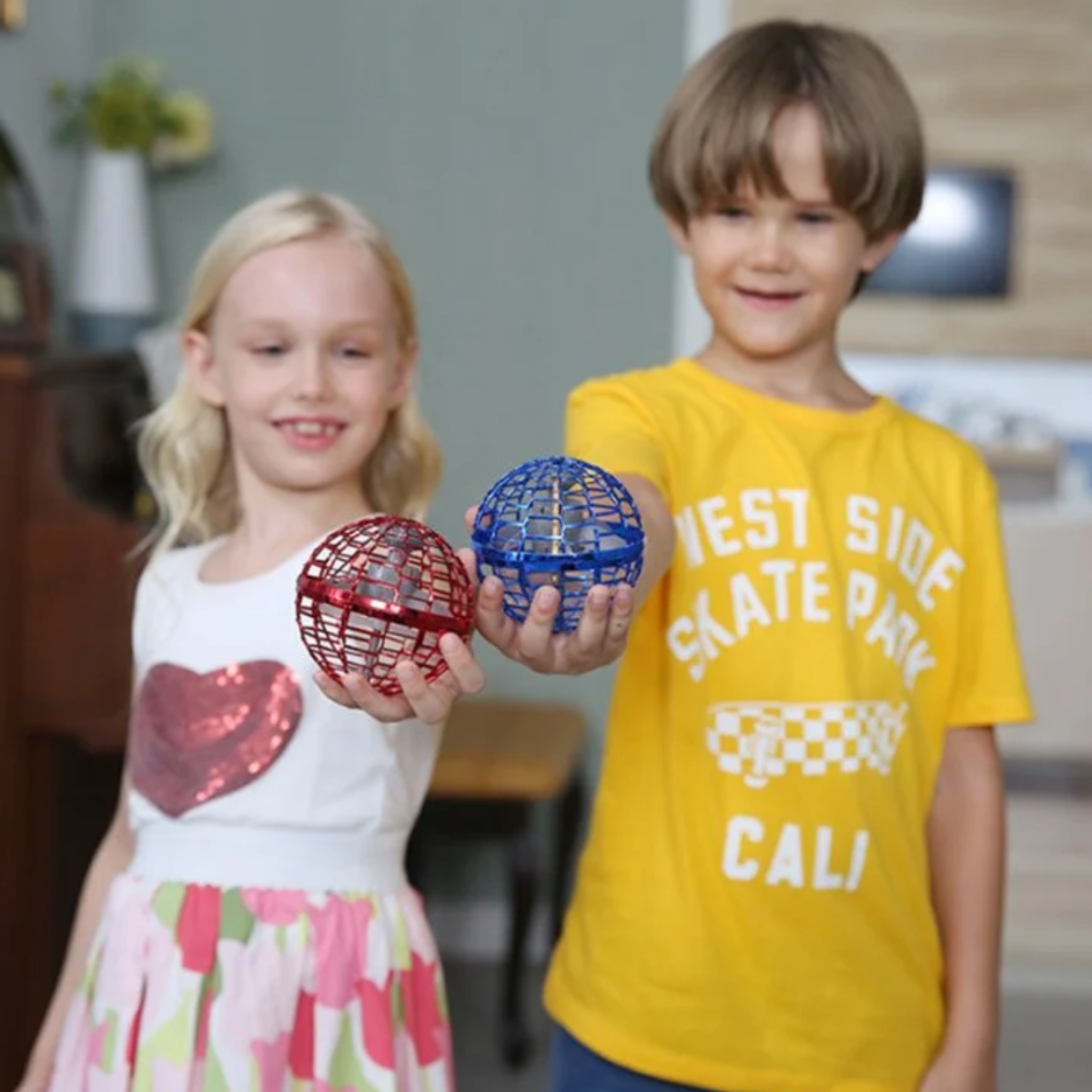 Two children holding a red and a blue flying orb ball