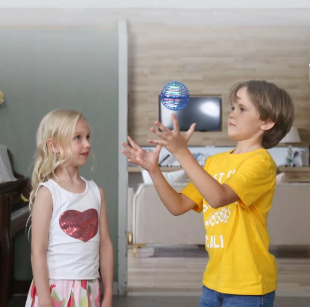 Child playing catch with a blue flying orb ball indoors