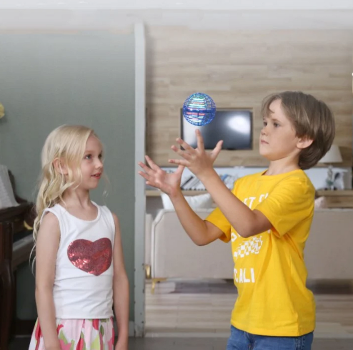 Child playing catch with a blue flying orb ball indoors