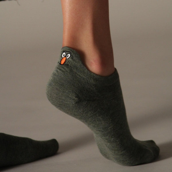 Side view of a green ankle sock with an embroidered character at the heel