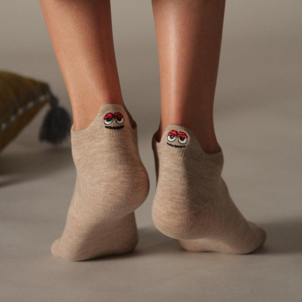 Woman wearing beige ankle socks with embroidered character at the heel, seen from behind