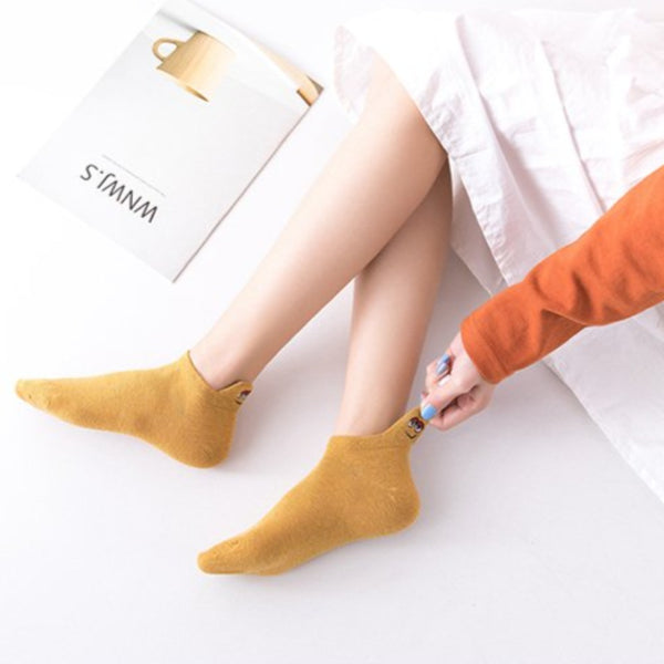 Mustard ankle socks being pulled on, showing the embroidered heel detail