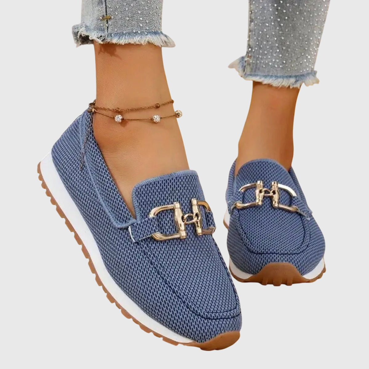 Angled view of blue mesh loafer trainers with gold-tone detail and white sole, worn