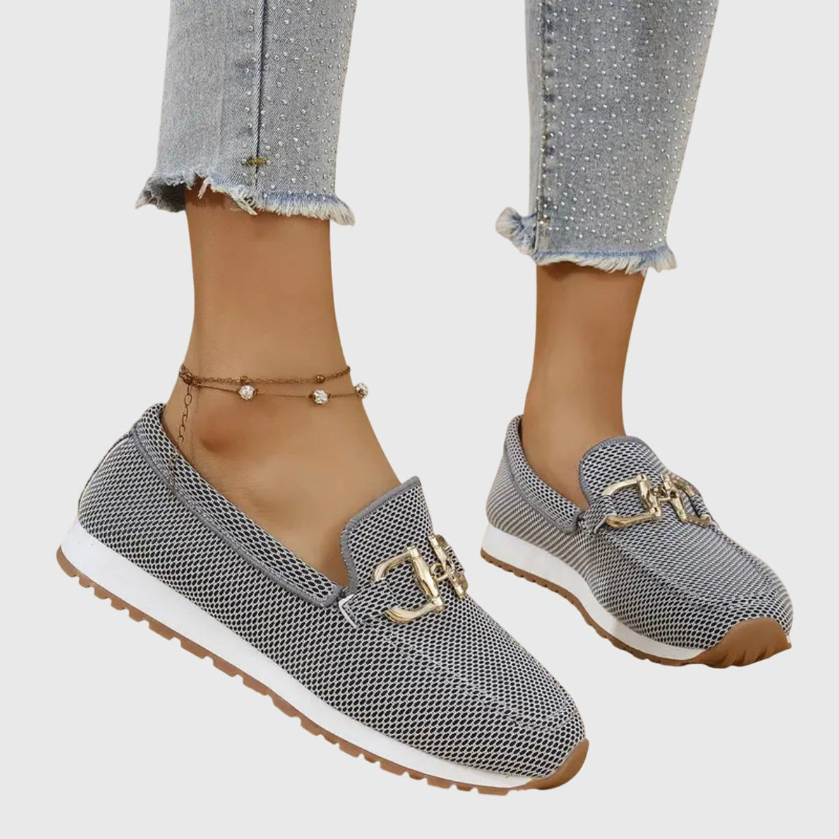 Grey mesh loafer trainers with a gold-tone detail and white sole, worn, angled view