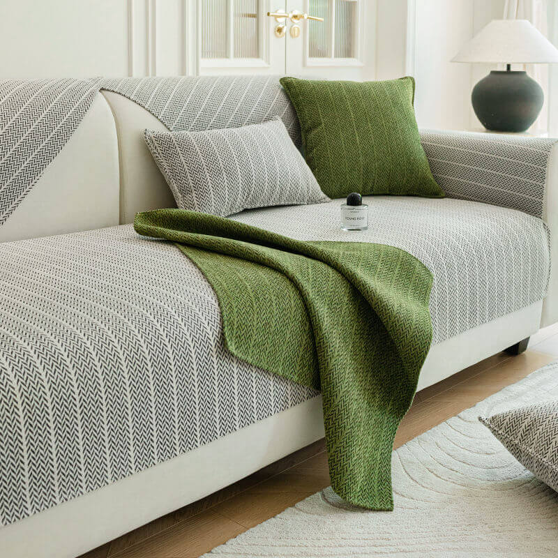 Light grey herringbone sofa cover with a green herringbone throw and cushion