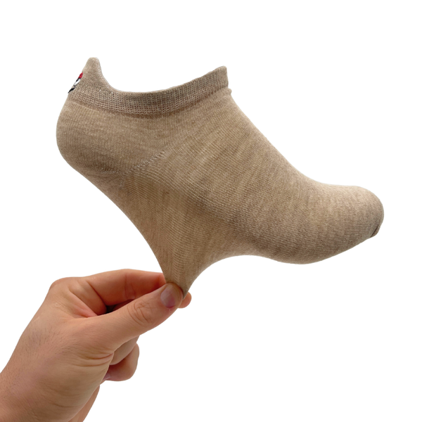 Hand holding a beige low-cut ankle sock to show its shape and stretch