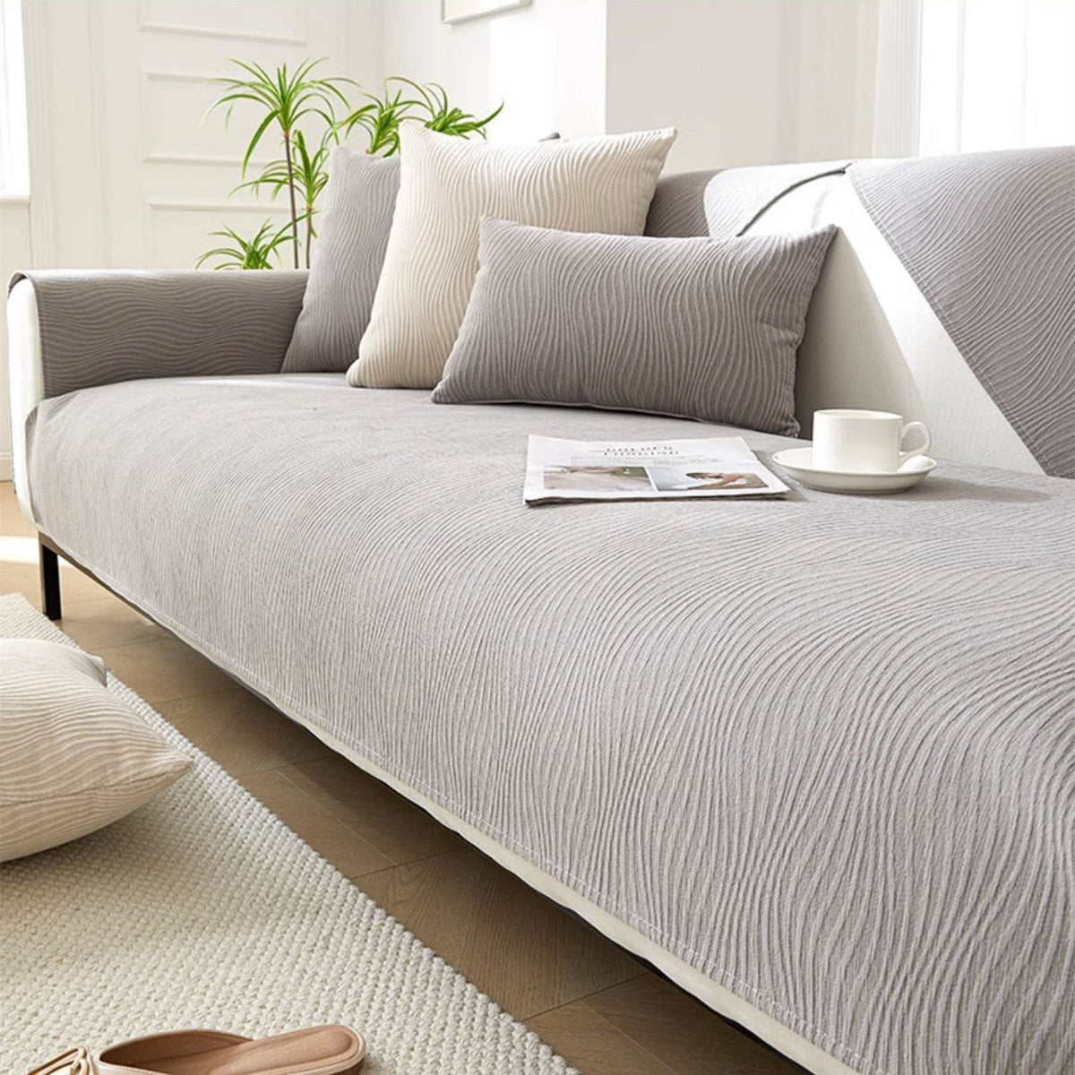 Light grey textured fabric sofa cover over a sofa seat and armrest in a bright living room