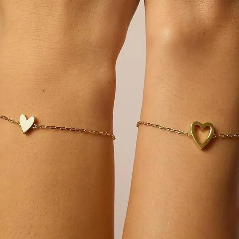 Close-up of a solid heart bracelet and an open heart bracelet worn on the wrists