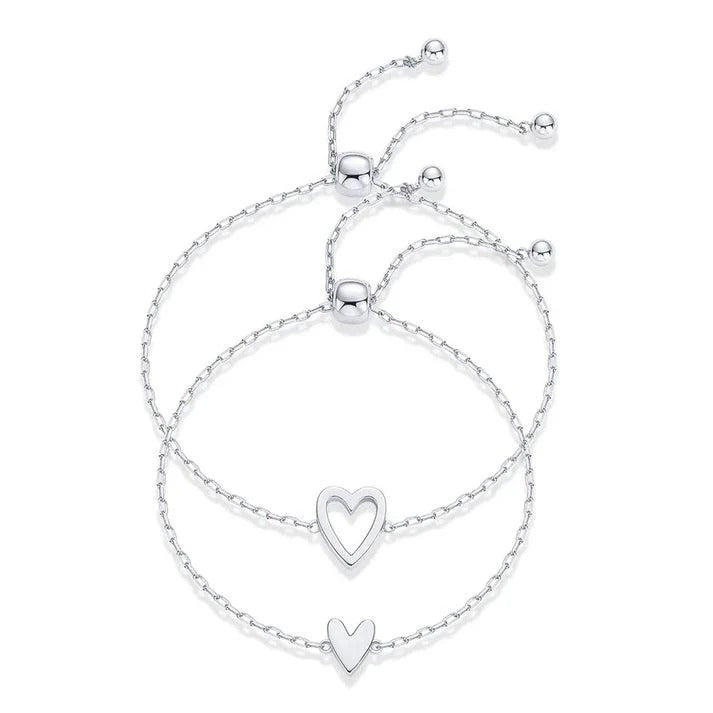 Two silver-tone chain bracelets with an open heart and a smaller solid heart detail