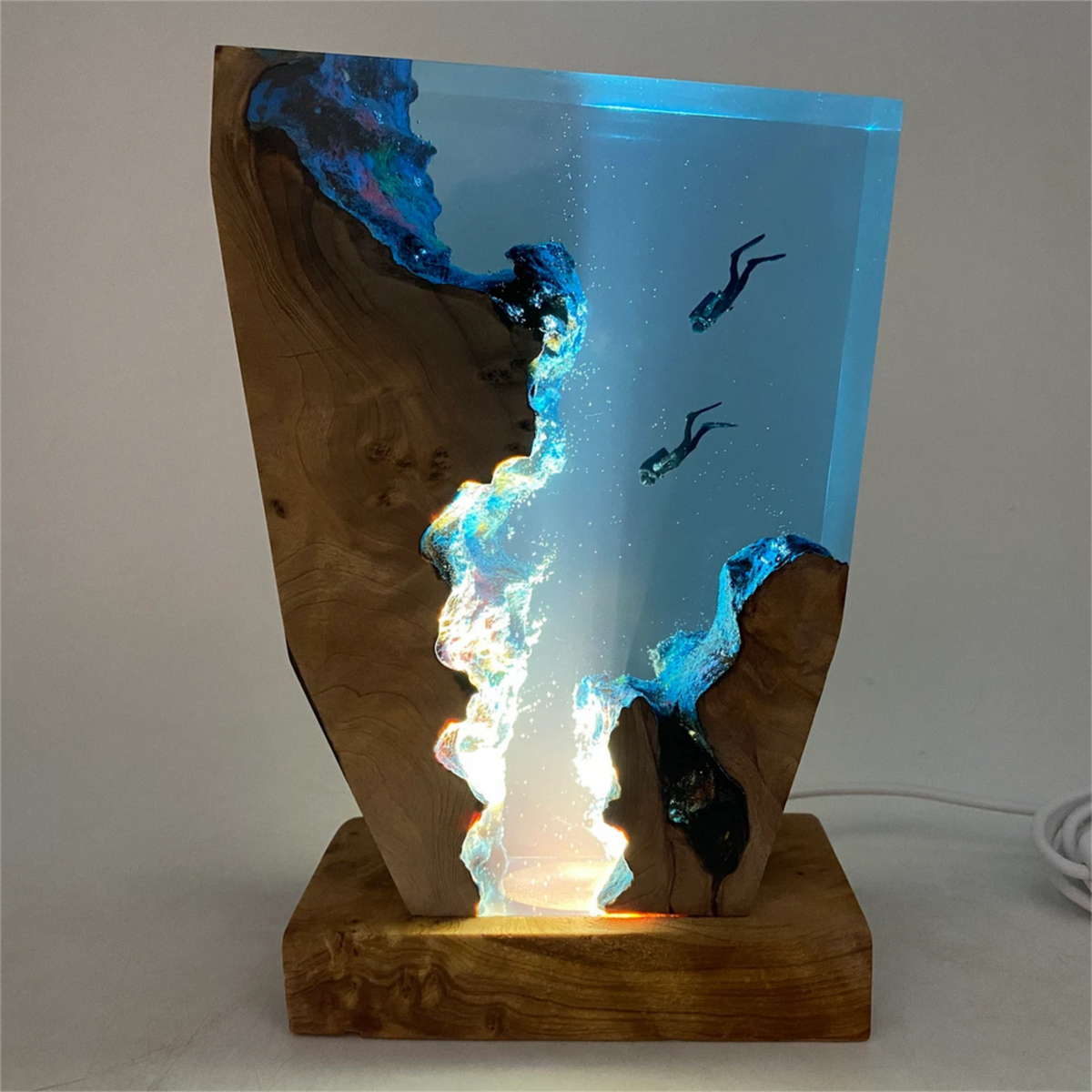 Front view of wooden table lamp with glowing blue panel and two diver silhouettes