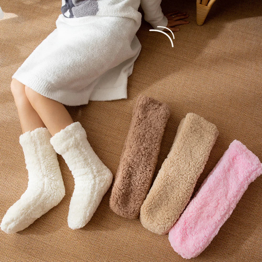 White fluffy socks worn with brown, light brown and pink pairs laid out on a woven rug