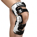 Black and white hinged knee brace worn on a leg with adjustable straps and padded frame