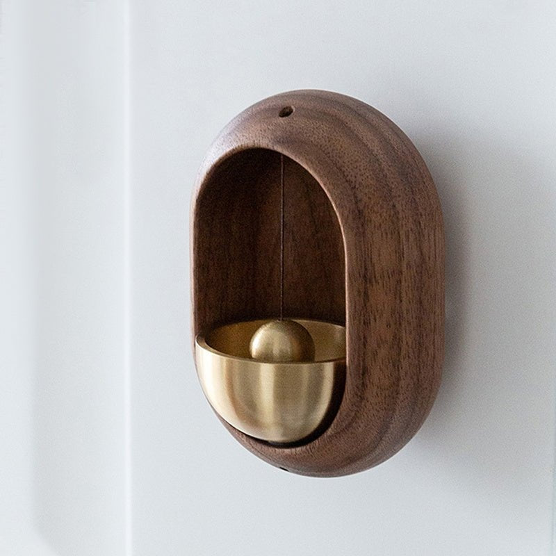 Brown wood-effect oval door bell with gold-tone bell mounted on a pale wall