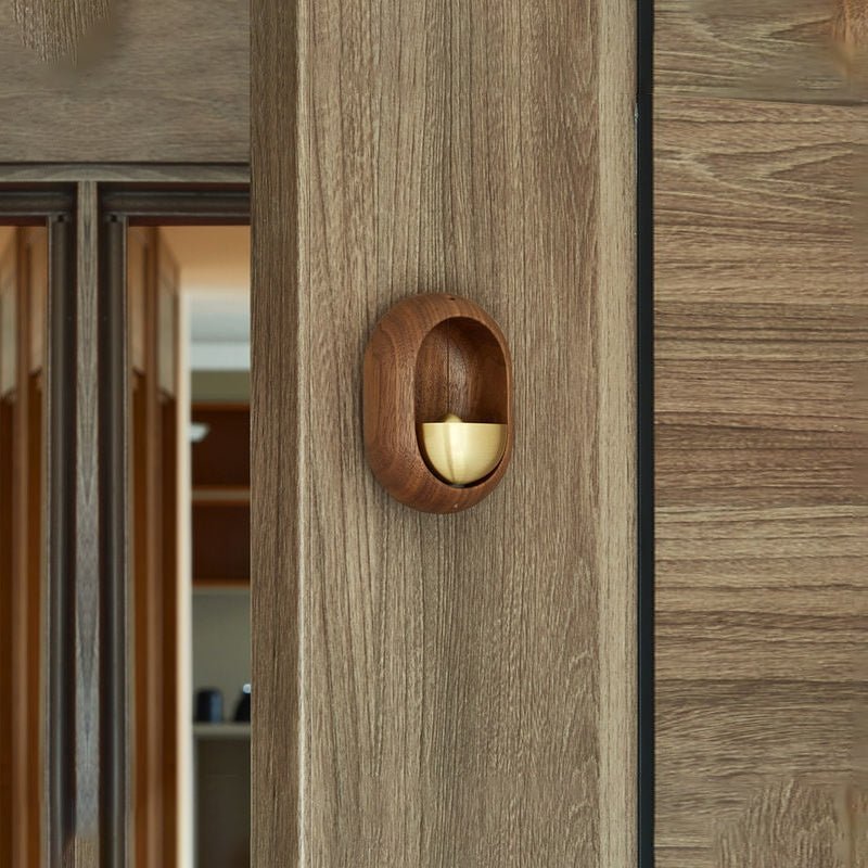 Brown wood-effect oval door bell with gold-tone bell on a wooden door frame