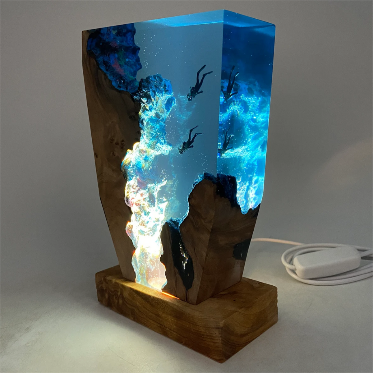 Side view of sculptural wooden lamp showing diver silhouettes and blue glow