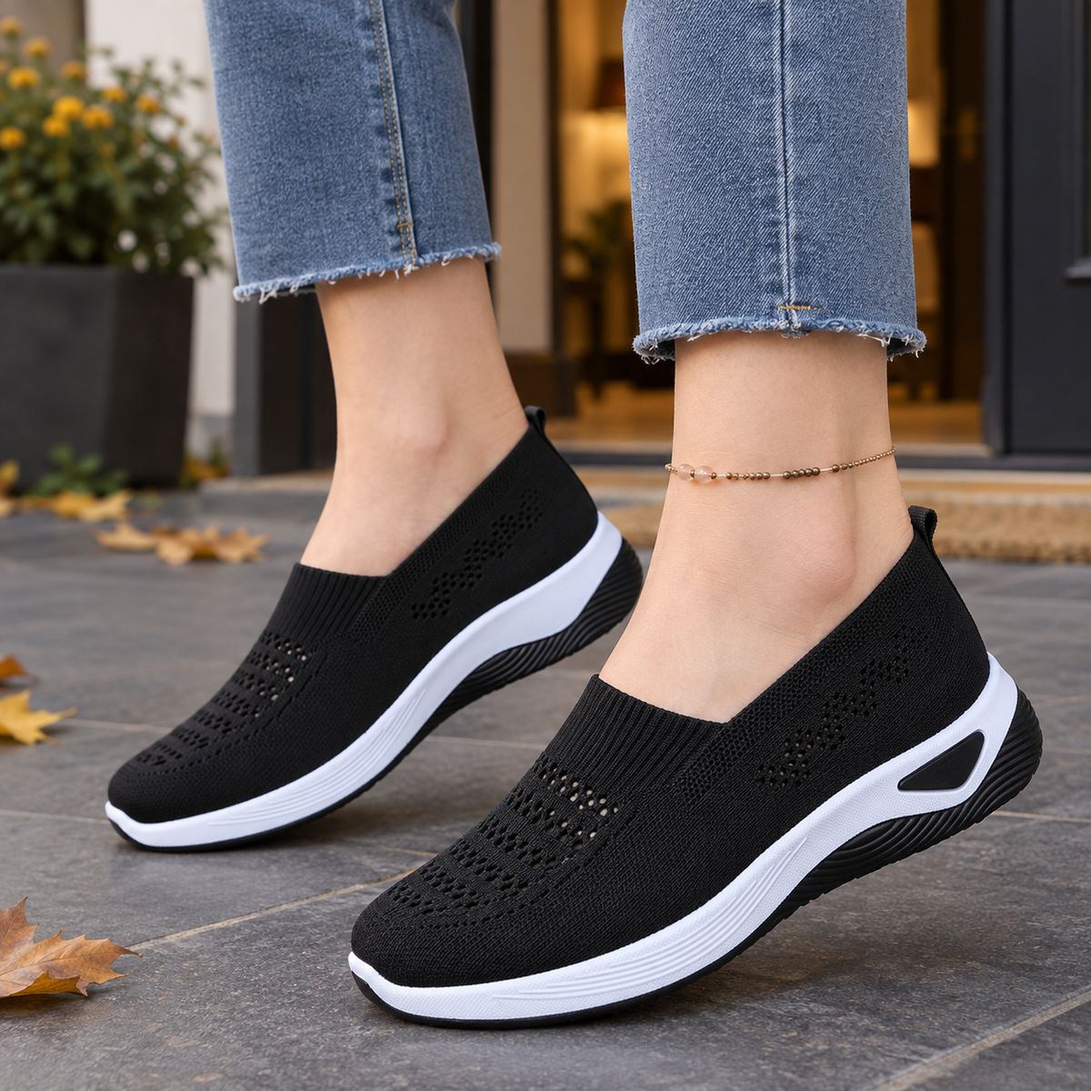 Black breathable knit slip-on sneakers for women with ventilated panels and white raised sole, worn with frayed-hem jeans