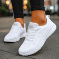 Women's knit walking trainers in white, lace-up trainers worn on a paved street