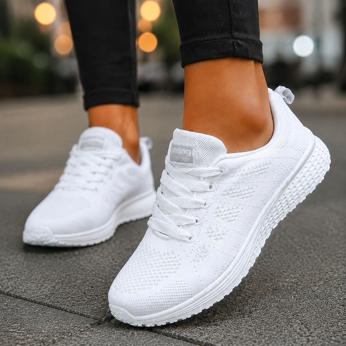 Women's knit walking trainers in white, lace-up trainers worn on a paved street