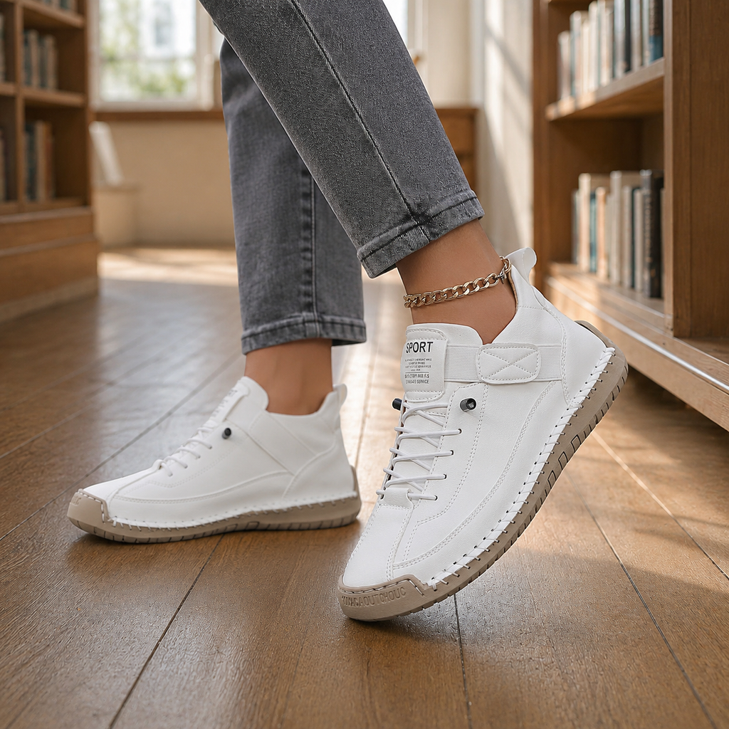 White leather lace-up sneakers with elastic strap and beige stitched sole, worn with grey jeans