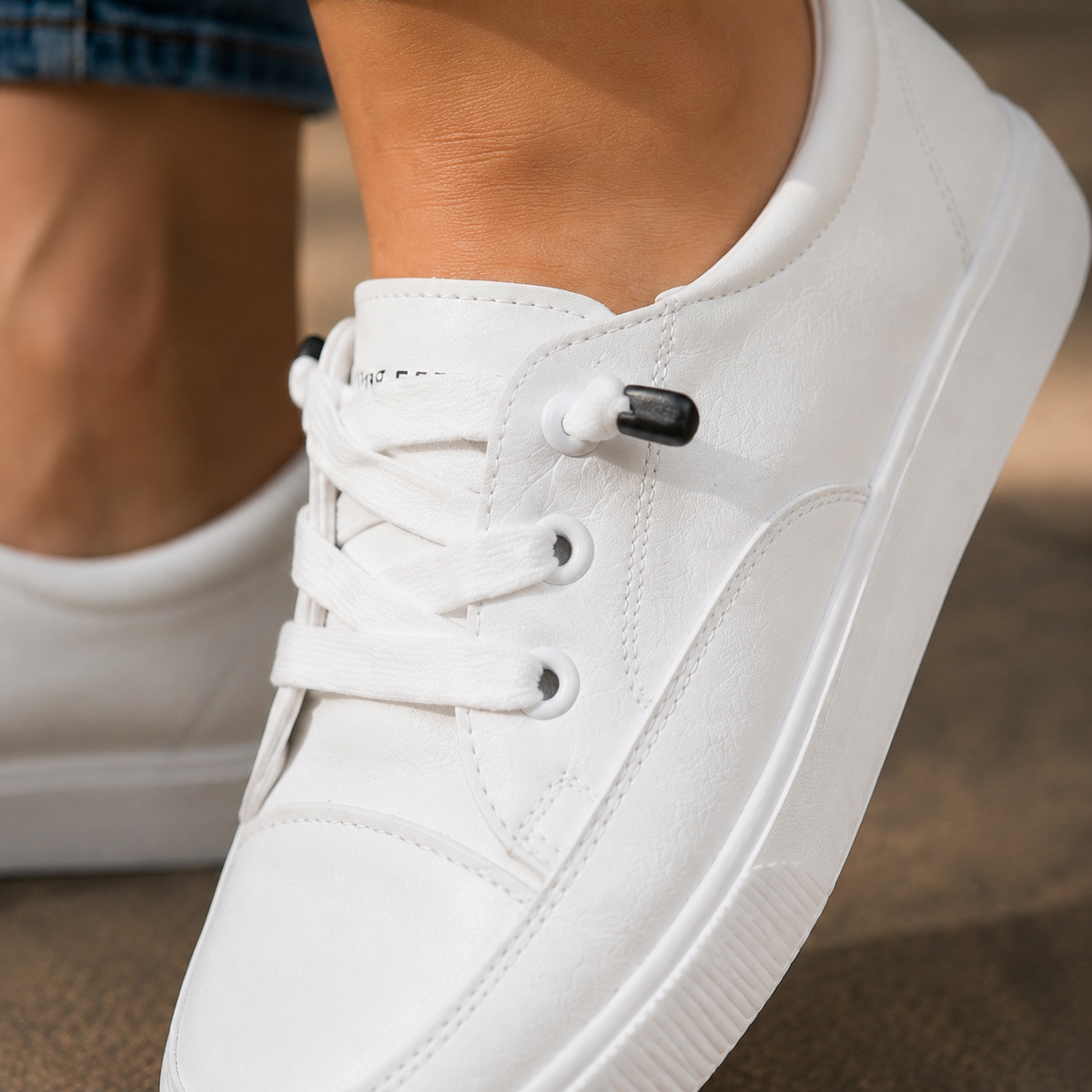 Close-up of the white low top trainers showing laces and eyelets