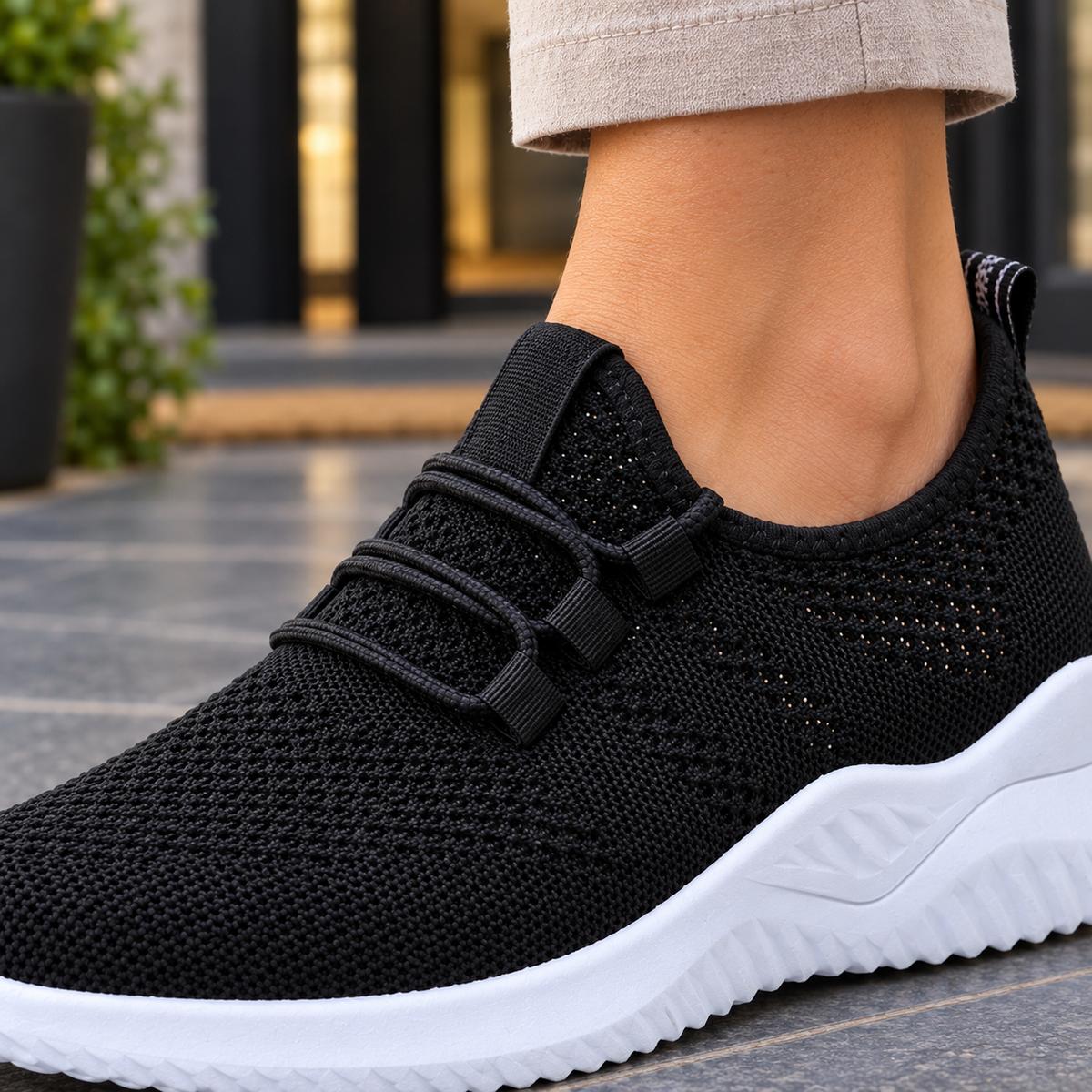 Close-up of black mesh-knit trainers with elastic laces and a cushioned white sole