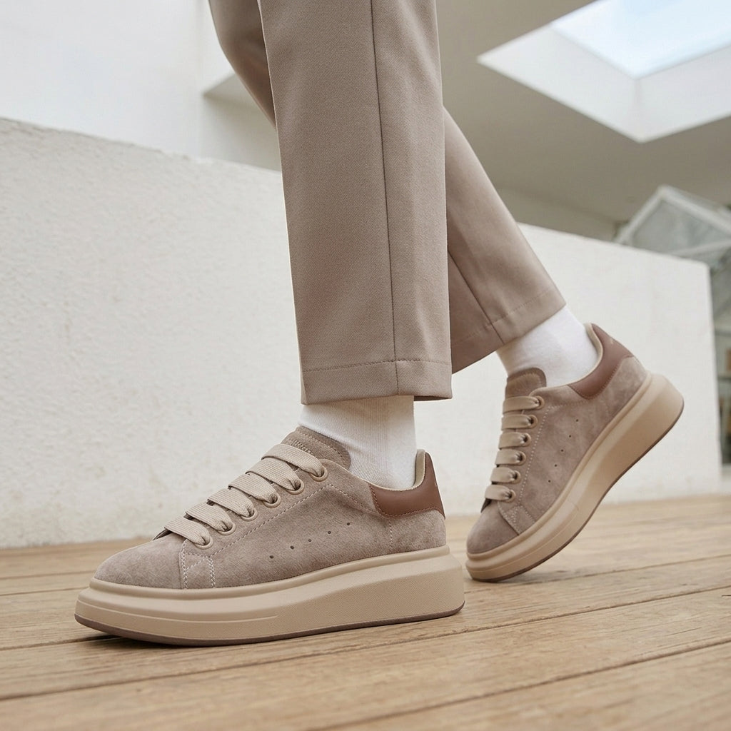 Side view of apricot taupe suede platform sneakers with a brown heel tab and a thick cream sole.