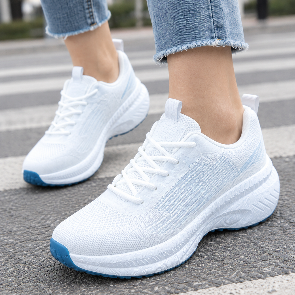 Close-up of white mesh knit lace-up trainers with light blue streaks, thick white platform sole and blue toe outsole