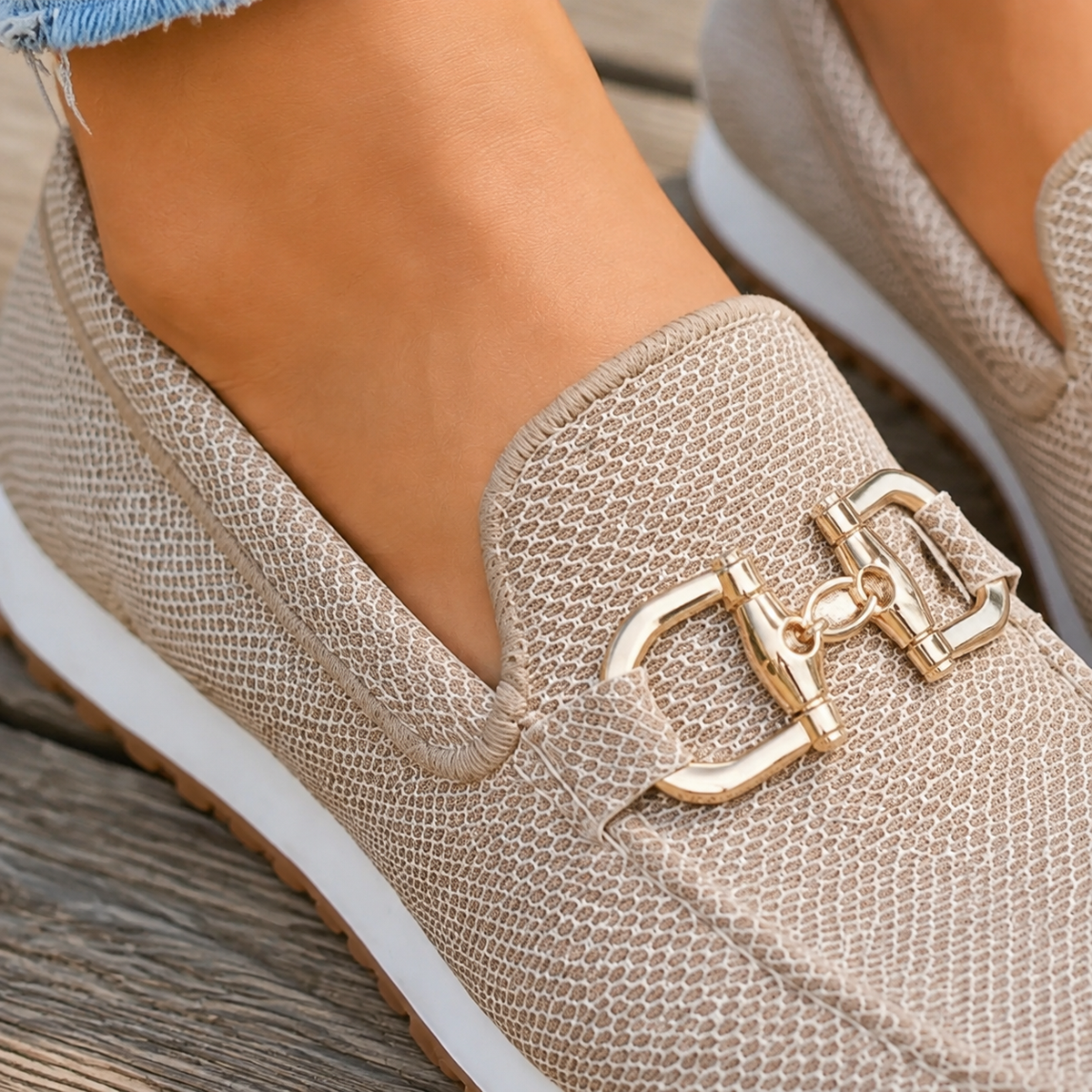 Close-up of the gold-tone buckle detail and woven texture on beige slip-on loafer trainers