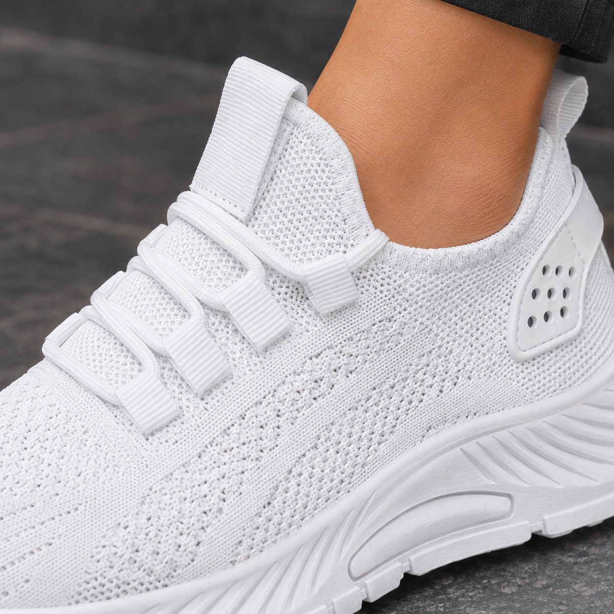 Close-up of a white knitted mesh trainer showing the laces and the platform sole.