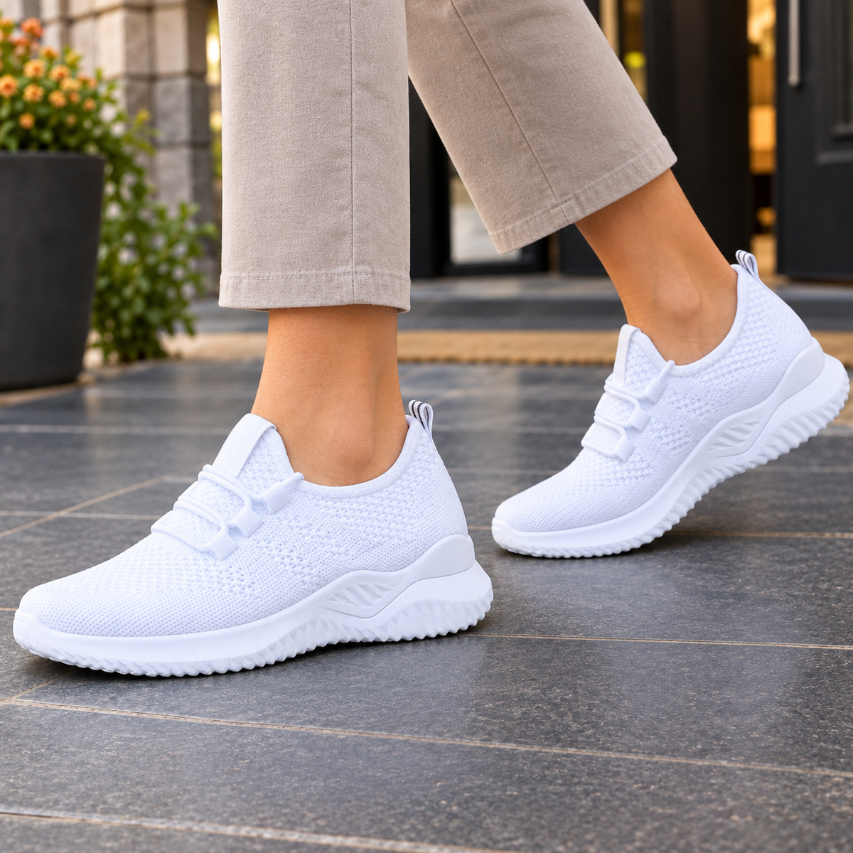 Pair of white mesh-knit trainers with elastic laces worn with cropped trousers