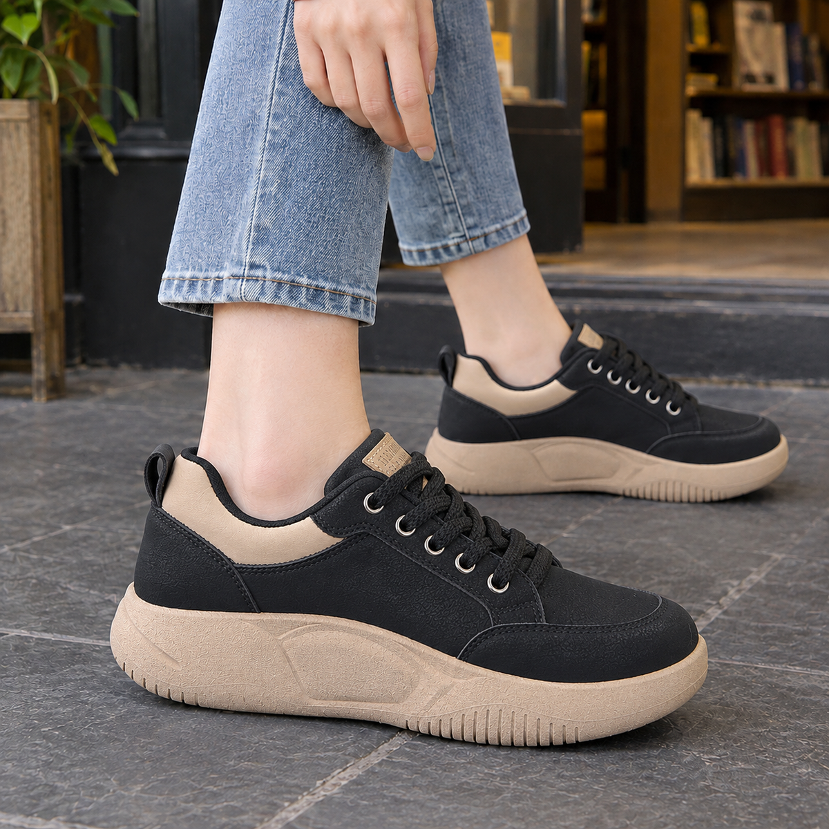 Black low-top platform trainers with beige heel panel and thick beige sole, worn with jeans