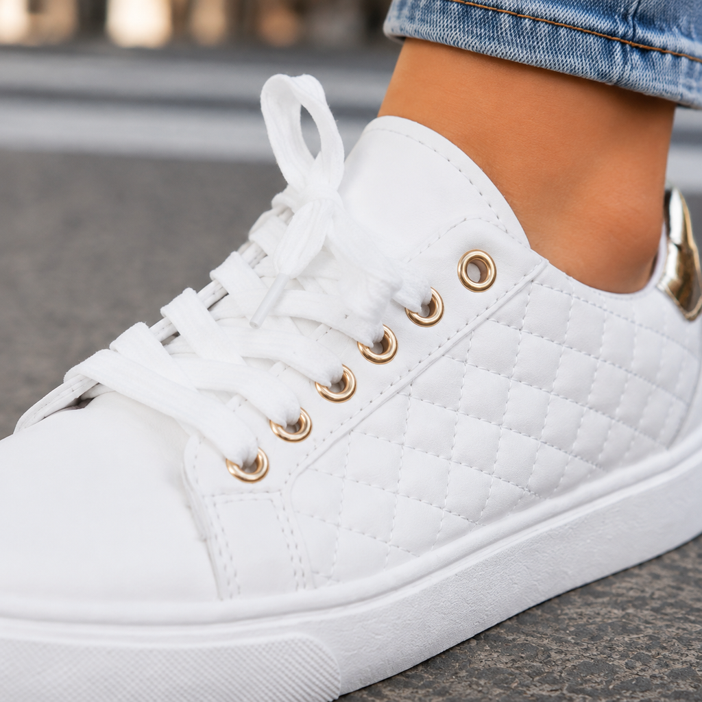 Close-up of a white quilted sneaker showing white laces, gold-tone eyelets, diamond stitching and chunky white sole