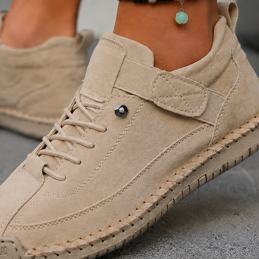 Close-up of a beige sneaker showing elastic laces, hook-and-loop strap tab and stitched sole edge.
