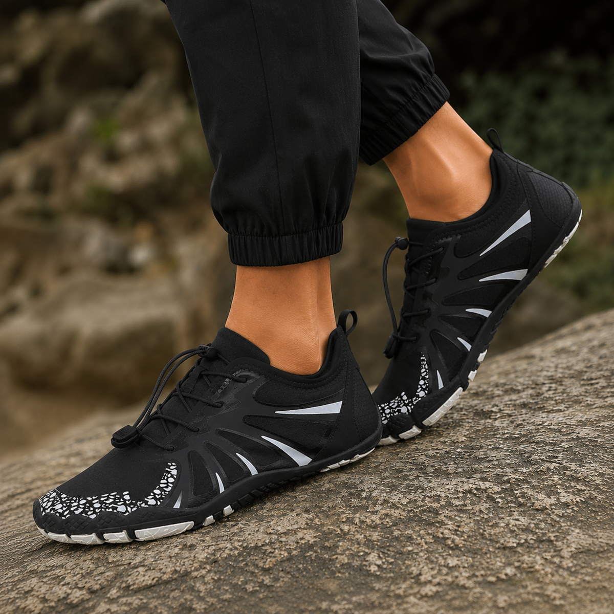 Black barefoot water shoes with white accents on a rocky surface