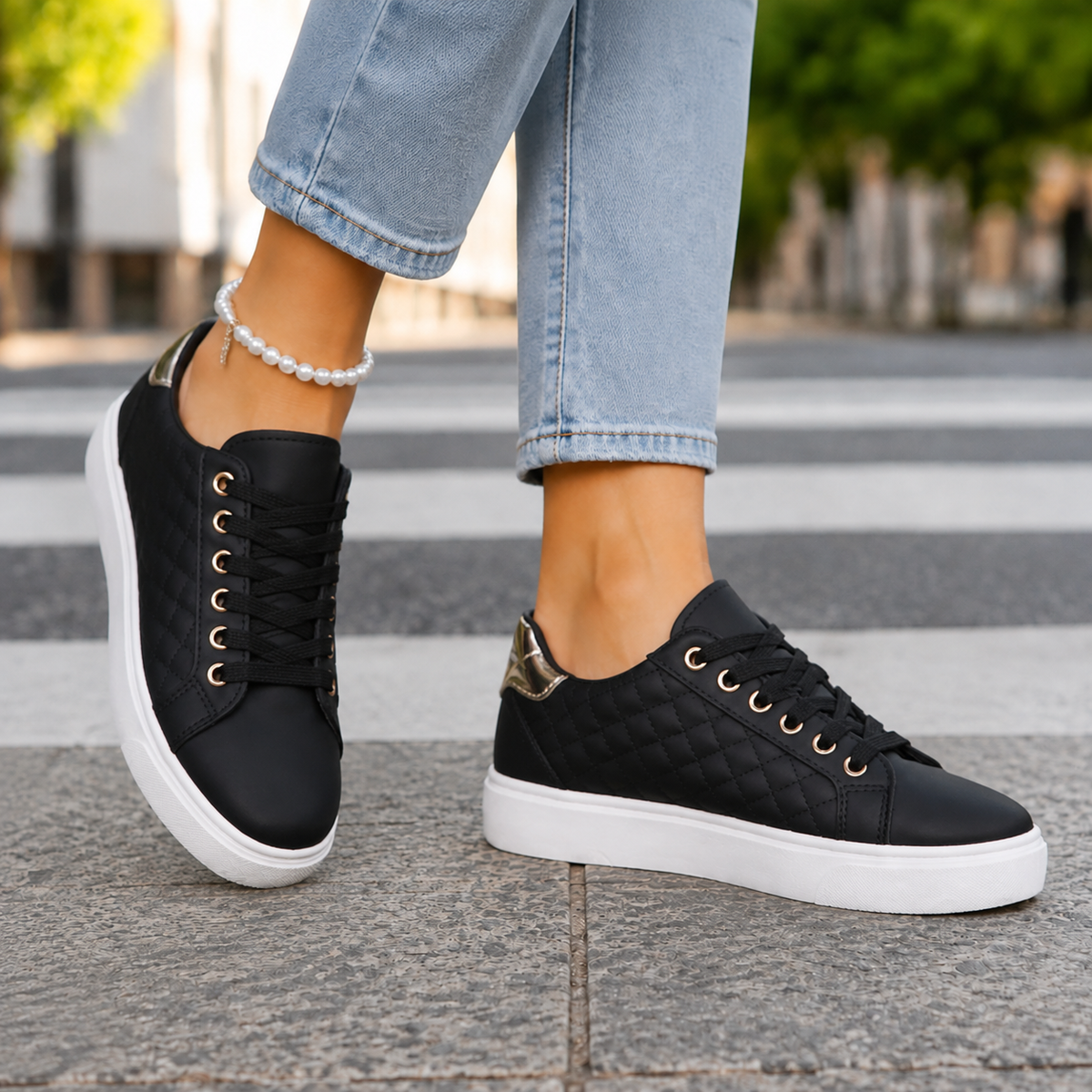 Black quilted low-top trainers with chunky white soles and gold-tone eyelets, worn with light blue jeans
