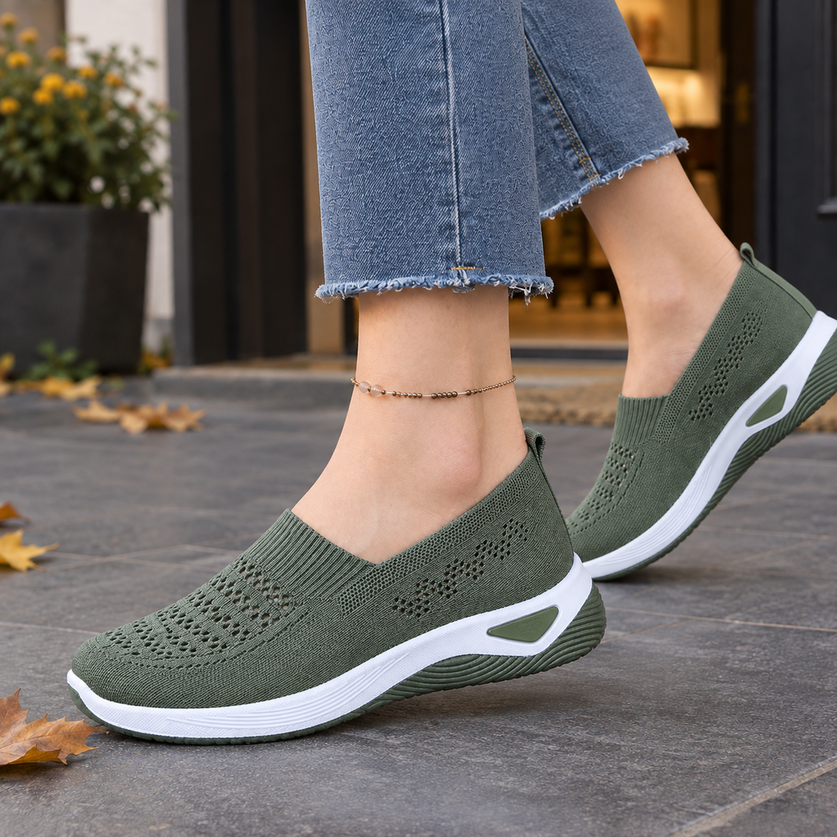 Military green knit slip-on trainers with a white raised sole, worn outdoors with jeans