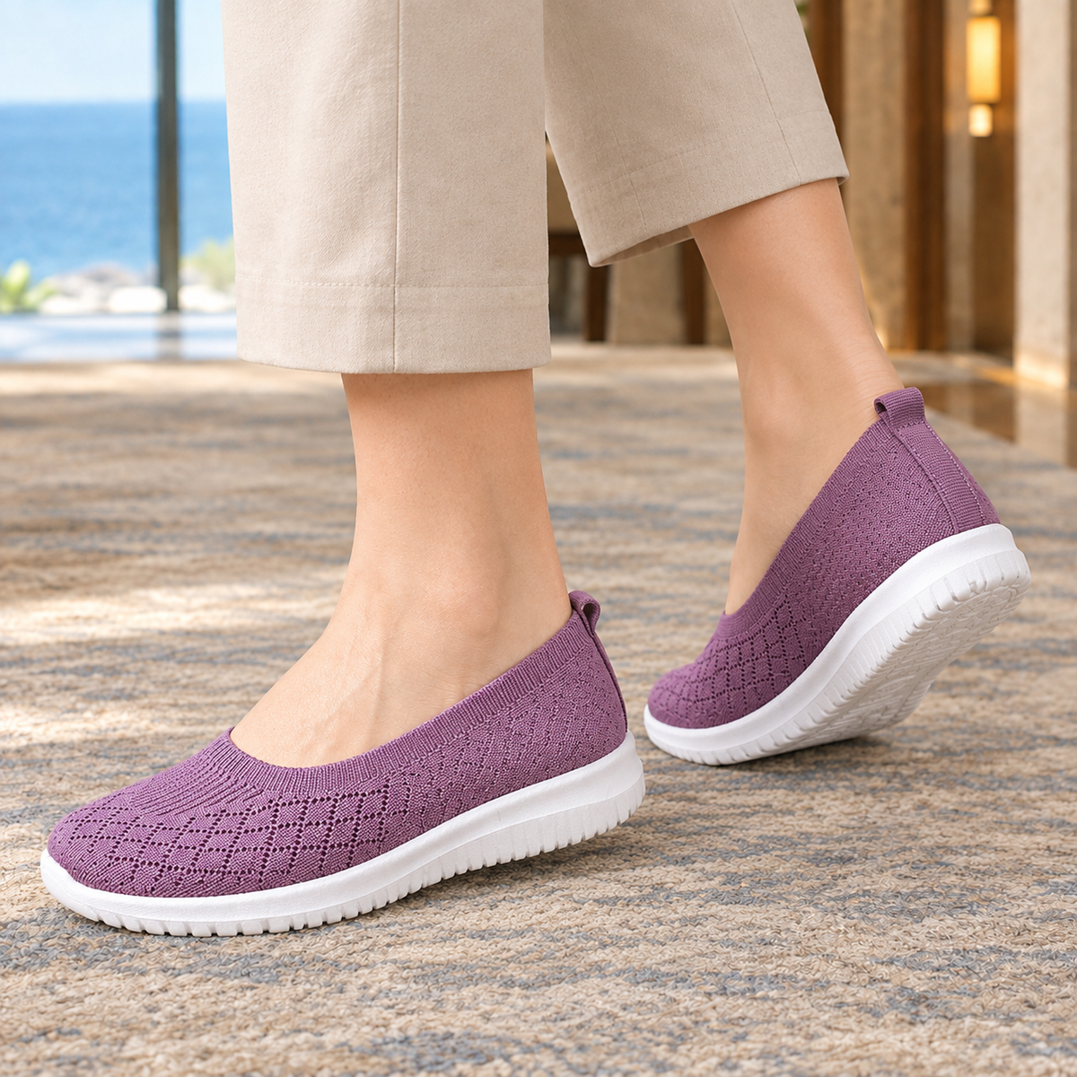 Purple knitted slip on trainers seen from the side and back, showing the heel loop and sole profile.