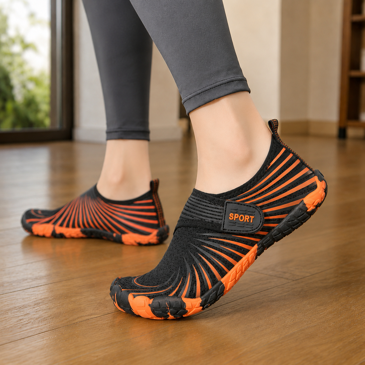 Black and orange five toe aqua shoes with a ridged sole, worn on a wooden floor