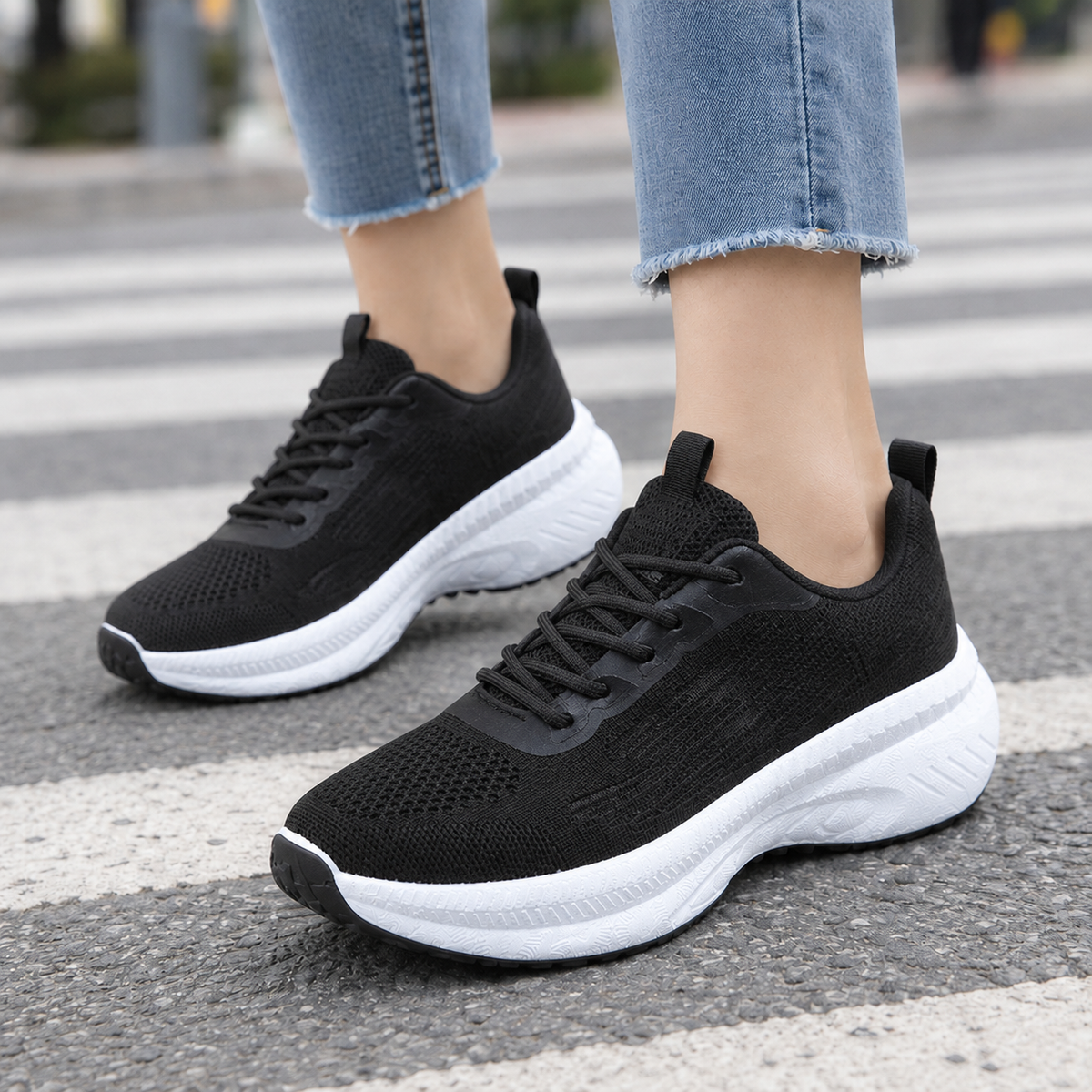 Black mesh knit lace-up trainers with thick white platform sole and black outsole, worn with frayed light jeans