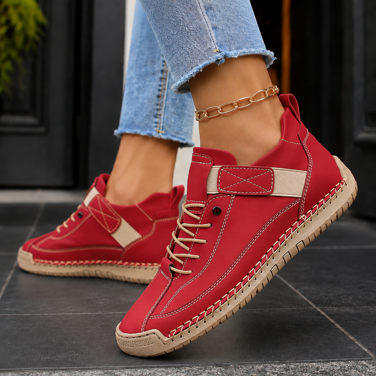 Red lace-up sneakers with cream elastic strap, cream laces and a cream stitched sole.