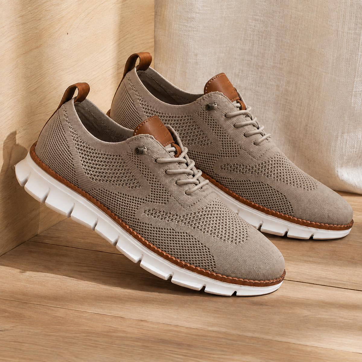 Pair of brown knit sneakers with a white ridged sole, angled view on a wooden floor