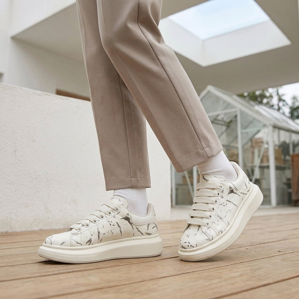 White leather platform sneakers with a grey marbled print, flat laces and a thick white platform sole.