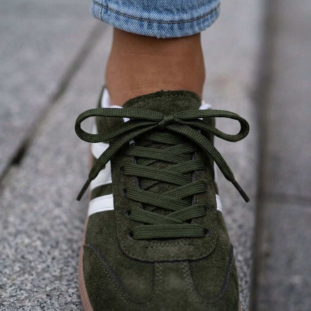 Close-up of dark green lace-up retro trainers with tonal flat laces and white panel detail