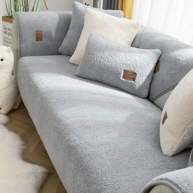 Grey textured teddy fleece sofa cover with matching cushion covers beside a fluffy rug