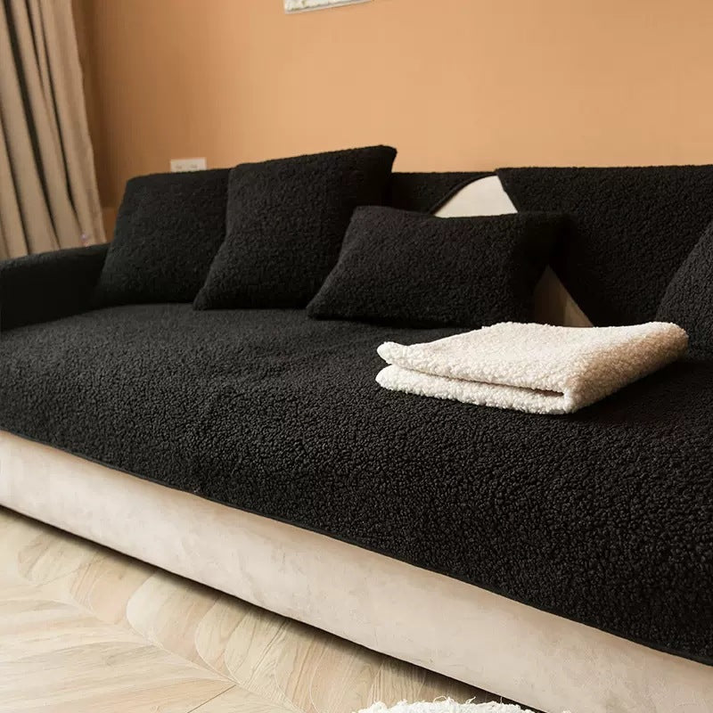 Black teddy fabric sofa cover with a folded cream throw on top